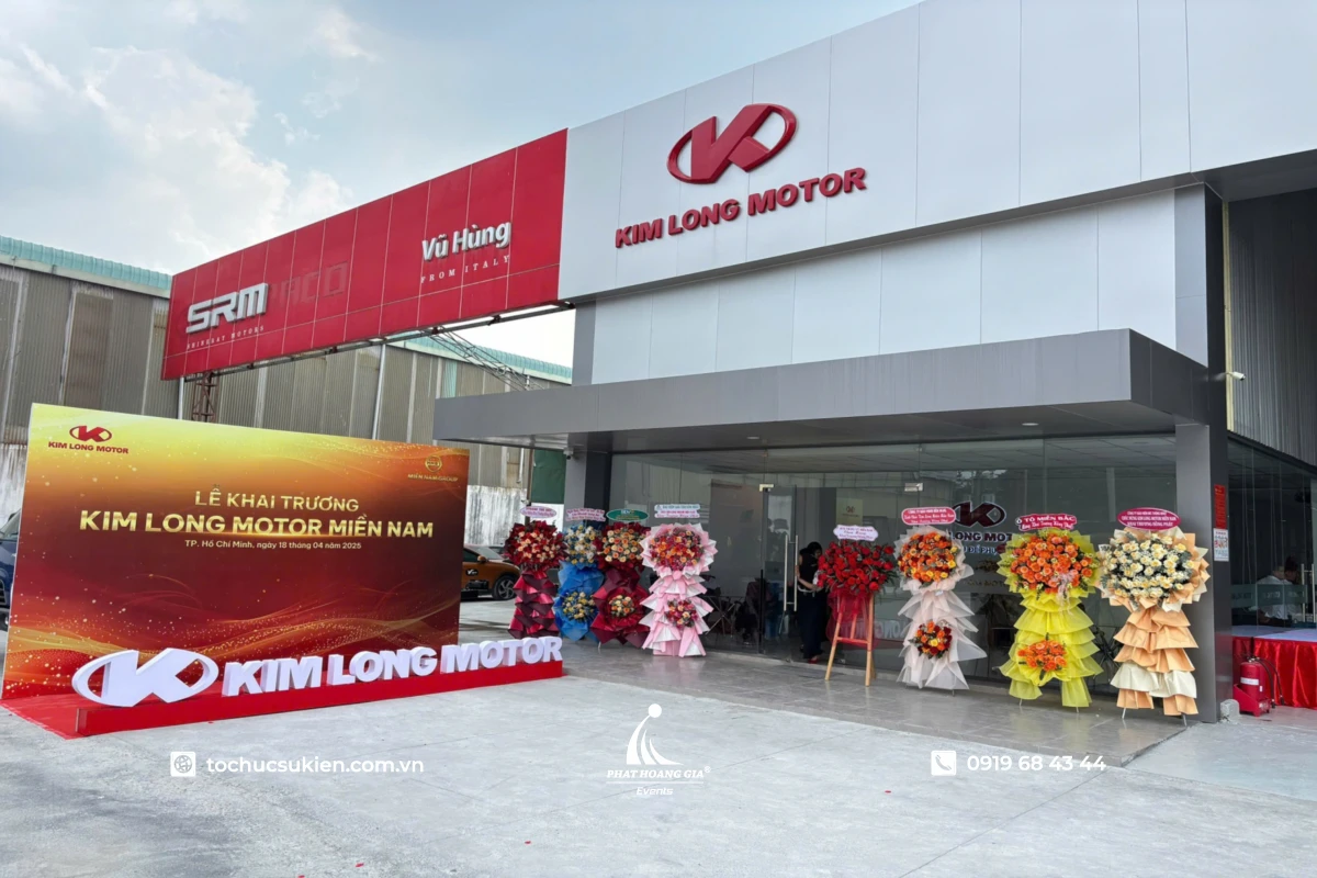 Toàn cảnh lễ khai trương với backdrop sự kiện và lẵng hoa chúc mừng bố trí hai bên lối vào doanh nghiệp