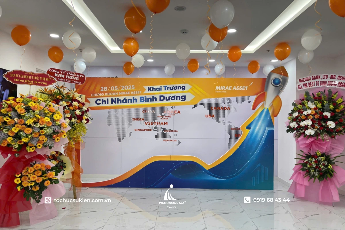 Backdrop khai trương chi nhánh doanh nghiệp với thiết kế concept hiện đại, bóng bay trang trí và lẵng hoa chúc mừng hai bên