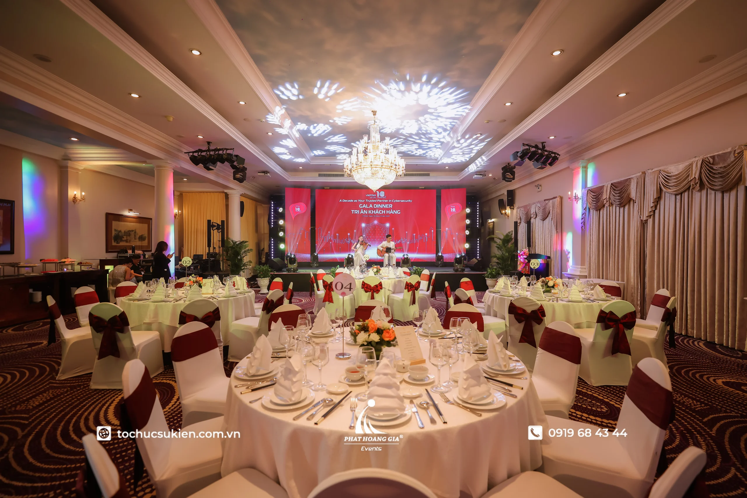 Toàn cảnh không gian gala dinner doanh nghiệp được bố trí theo kịch bản tiệc với sân khấu, bàn tiệc và hệ thống ánh sáng đồng bộ