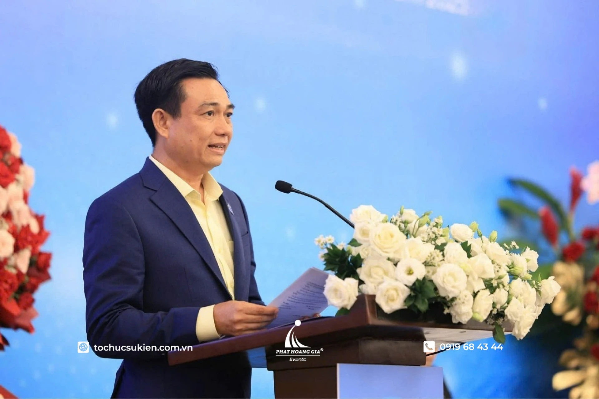 Đại diện doanh nghiệp phát biểu tại bục với micro và hoa trang trí trong hội nghị