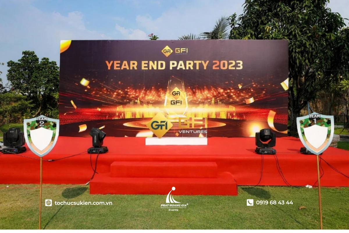 Sân khấu Year End Party ngoài trời với backdrop khung sắt, bục thảm đỏ và hệ thống đèn Moving Head chuyên nghiệp 