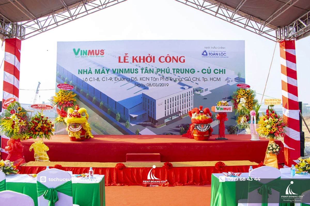 Sân khấu ngoài trời lễ khởi công nhà máy với khung giàn truss nhôm, backdrop bạt lớn và bục thảm đỏ