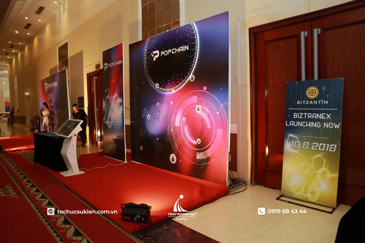 Standee dạng khung sắt quảng bá thương hiệu đặt cạnh backdrop tại sự kiện ra mắt sản phẩm công nghệ