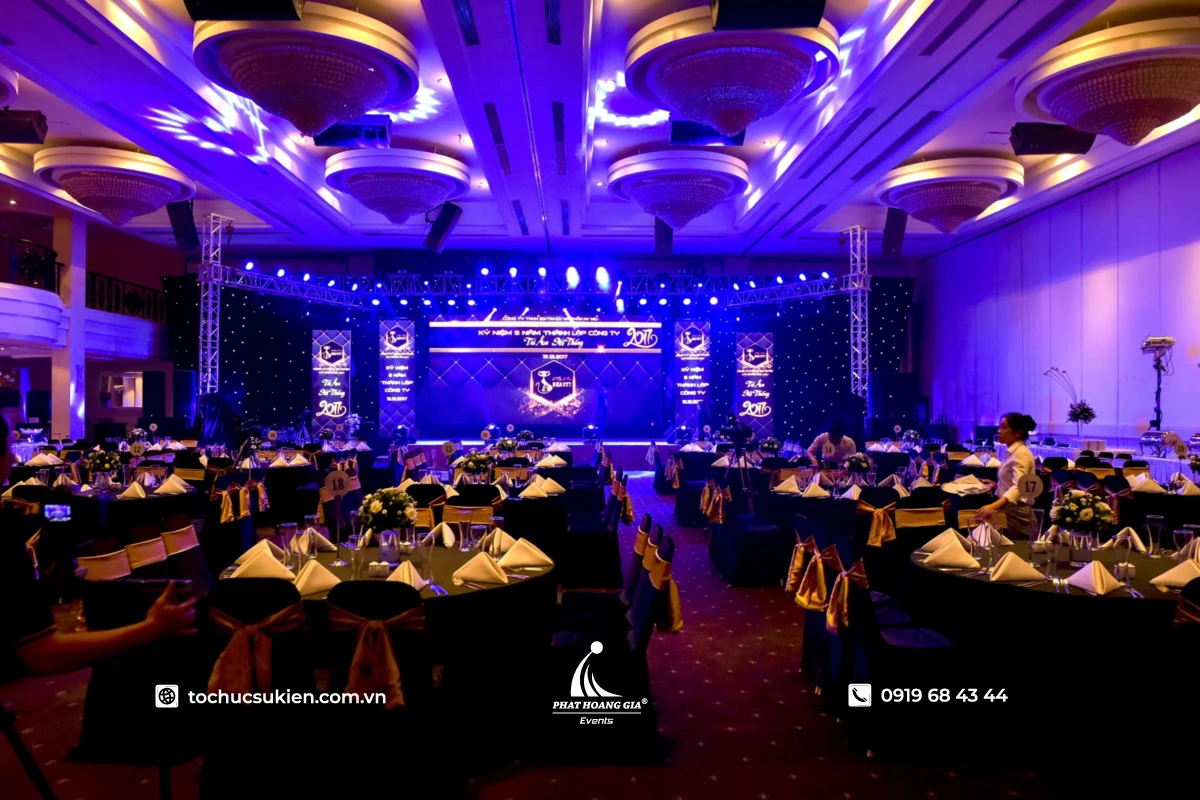 Không gian gala dinner công ty theme tím sang trọng với sân khấu LED, ánh sáng và bàn tiệc tròn đồng bộ