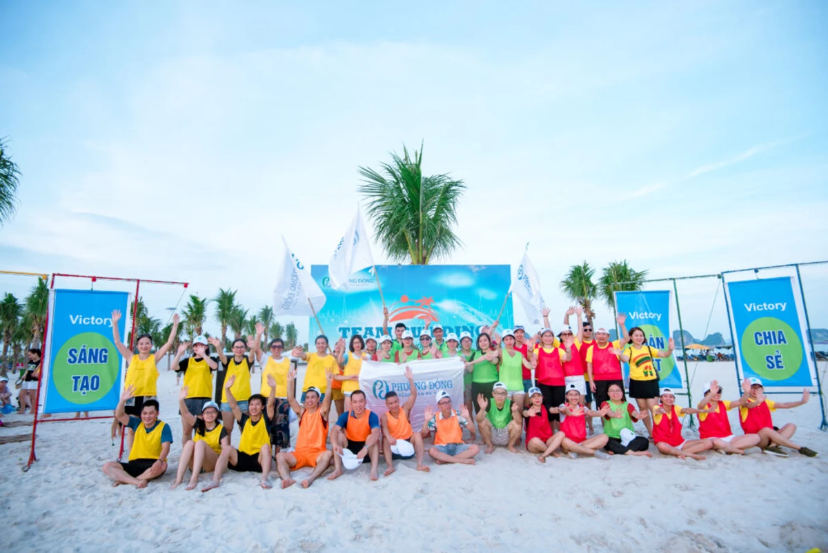 Tập thể nhân viên công ty check in trước backdrop teambuilding bãi biển màu xanh