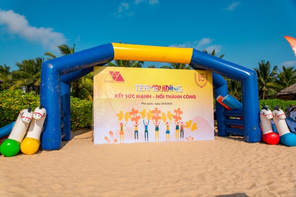 Toàn cảnh khu vực check in sự kiện ngoài trời có phao hơi và backdrop teambuilding bãi biển