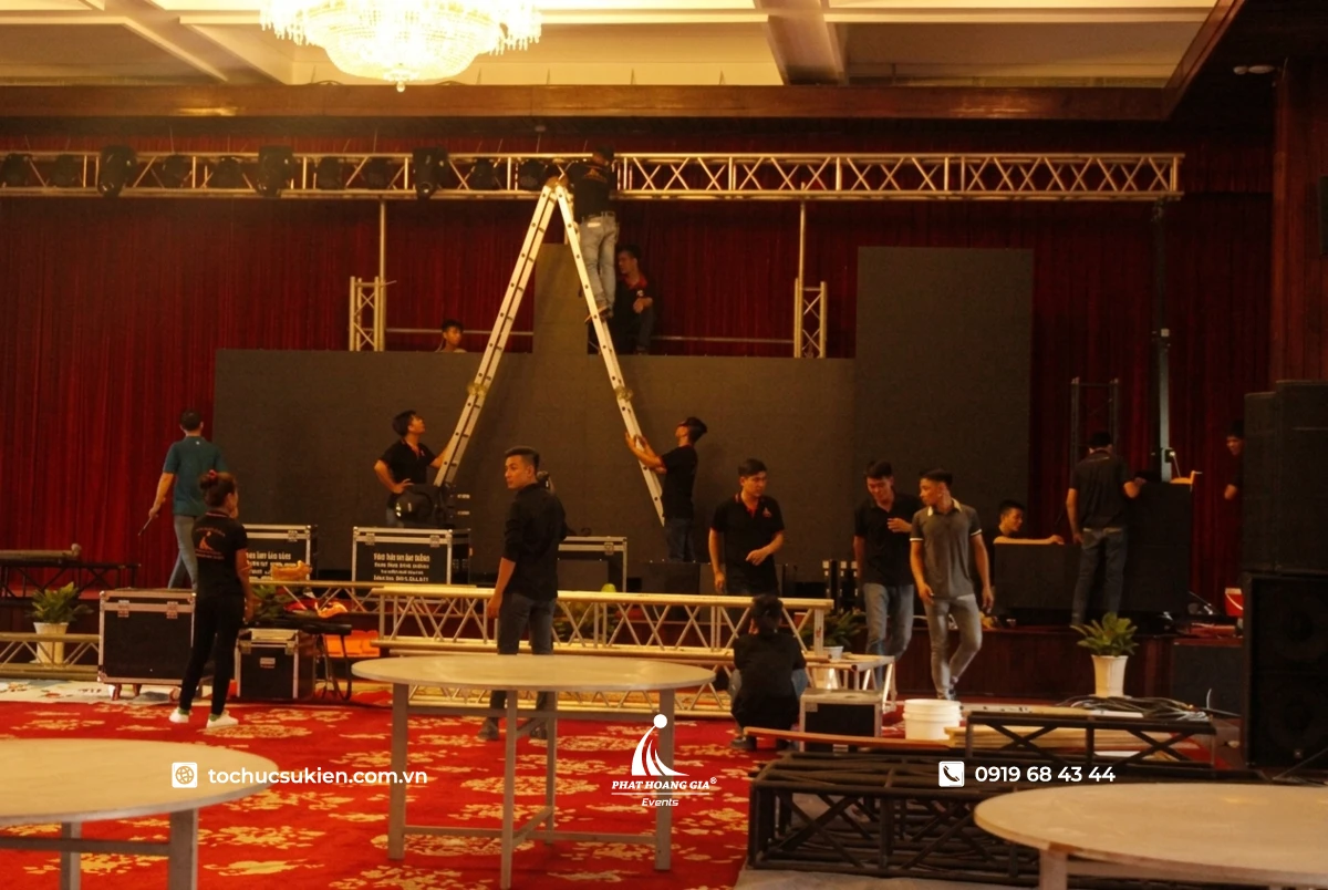 Ekip PHG thi công đang lắp đặt background hội nghị lên khung sắt tại sân khấu trước giờ sự kiện