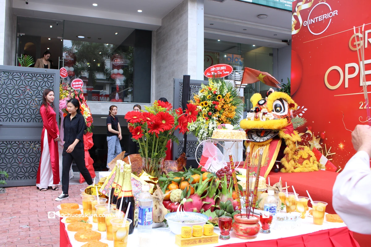 Mâm cúng khai trương ngoài trời trước showroom tại TP.HCM với heo quay, mâm ngũ quả, nhang đèn, hoa tươi và múa lân chuẩn bị cho nghi thức khai trương buổi sáng