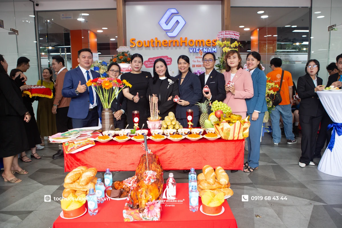 Ban lãnh đạo công ty chụp ảnh lưu niệm cùng nhân viên bên không gian doanh nghiệp và mâm cúng khai trương được chuẩn bị đầy đủ