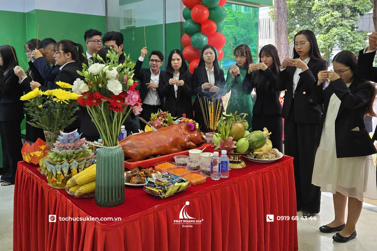 Lễ cúng khai trương với các nhân viên đang khấn trước mâm cúng được bày biện đầy đủ lễ vật truyền thống trong không gian công ty trang trọng