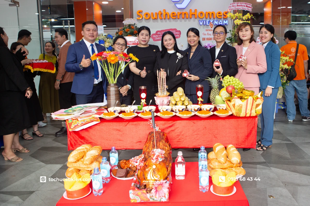 Tập thể nhân viên cùng chụp ảnh lưu niệm bên mâm cúng khai trương với đầy đủ lễ vật truyền thống trong không khí ấm