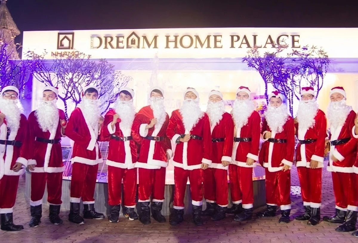 Những người mặc trang phục ông già Noel truyền thống tone đỏ trắng đang đứng xếp thành hàng trong không gian sự kiện Giáng sinh