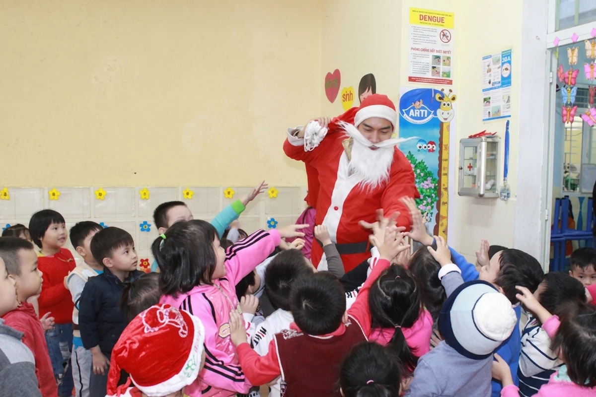 Ông già noel trong trang phục Giáng sinh truyền thống đang phát quà cho các em nhỏ tại sự kiện với không khí lễ hội ấm áp và vui nhộn