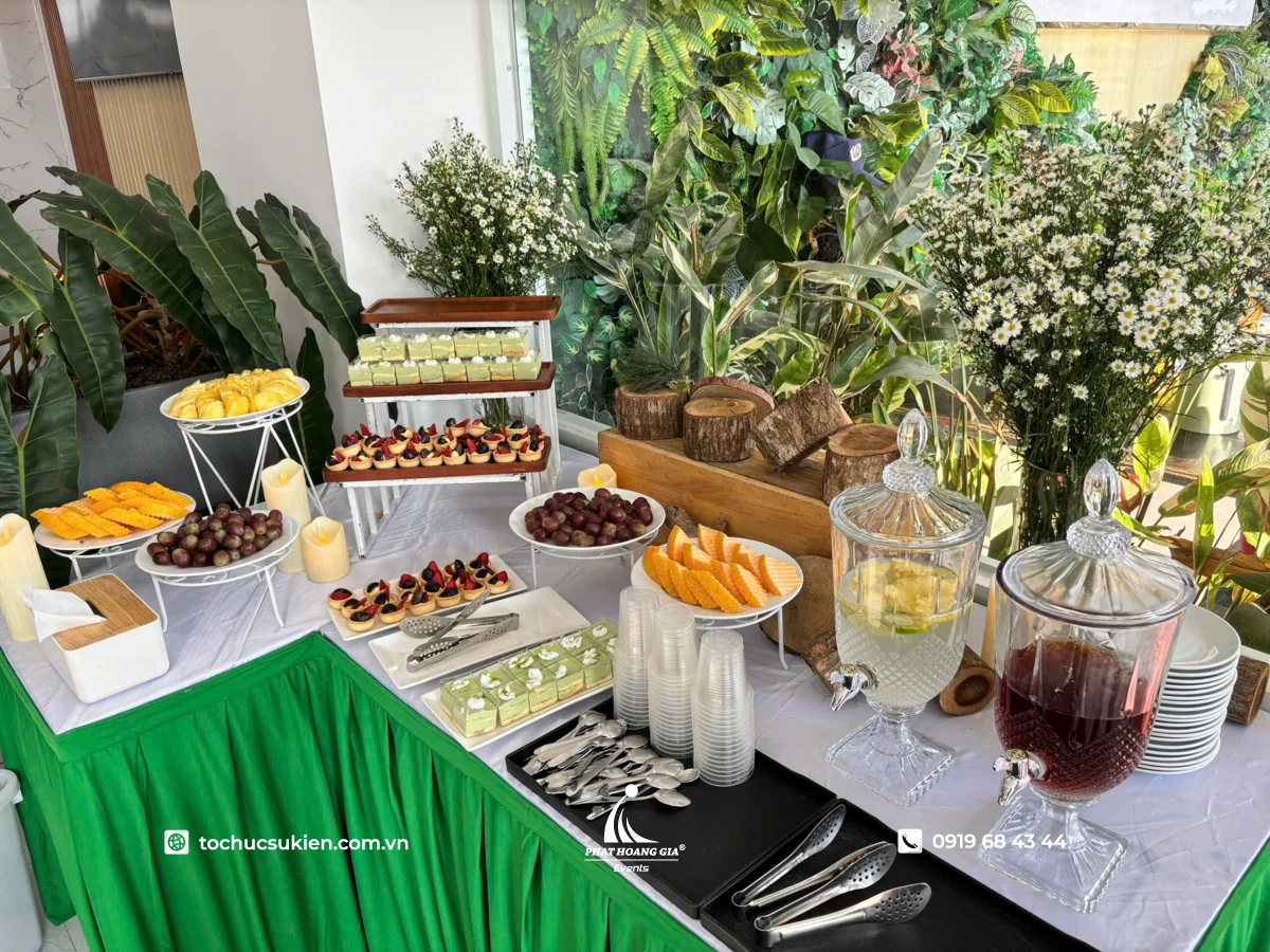 Bàn tiệc ăn nhẹ bày sẵn các khay bánh ngọt nhỏ cùng hai bình nước hoa quả trong ngày hội family day