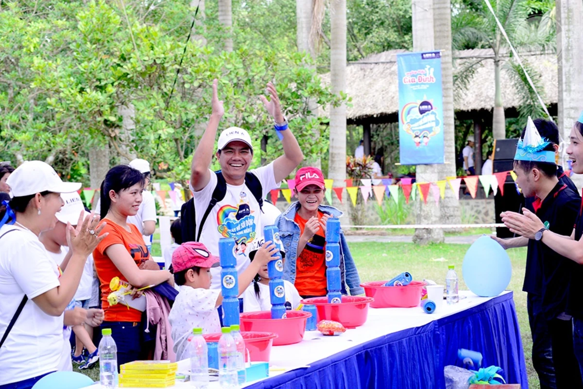 Family day náo nhiệt tại khu vực bàn trò chơi xếp lon được thiết lập vuông vắn trên bãi cỏ ngoài trời