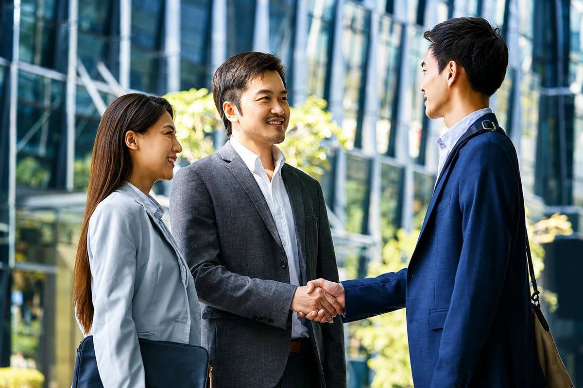 Khách hàng và đại diện doanh nghiệp vui vẻ bắt tay, trao đổi sau khi hoàn tất ký kết hợp đồng