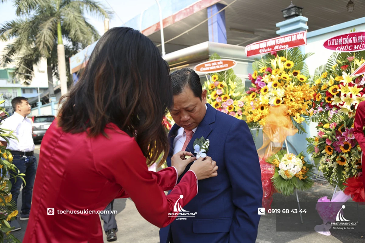 Lễ tân khánh tiết đang cài hoa chào đón đại biểu đến tham dự ngày lễ khánh thành đầy trang trọng.