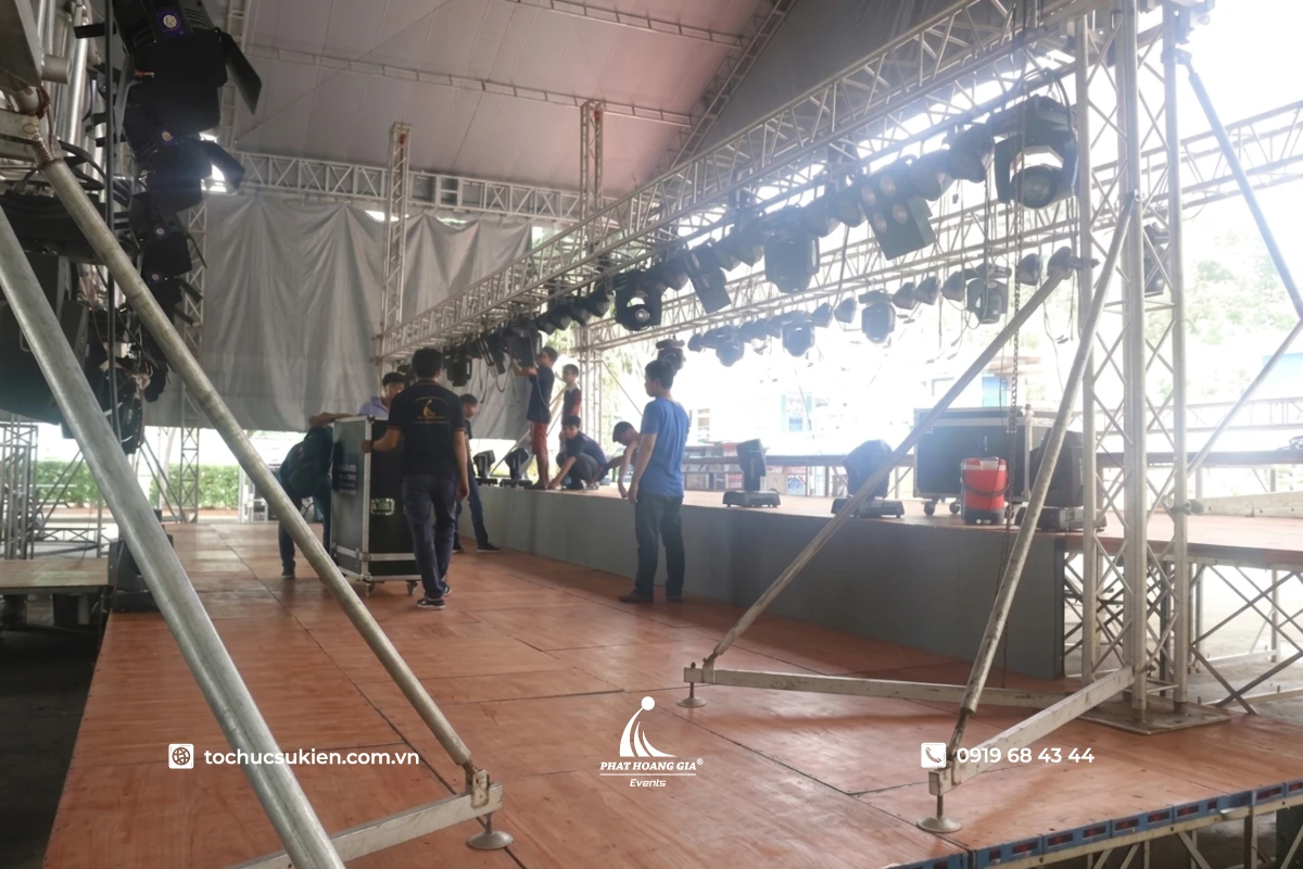 Ekip kỹ thuật PHG setup khung truss sân khấu với hệ thống đèn và dàn âm thanh tại sự kiện.