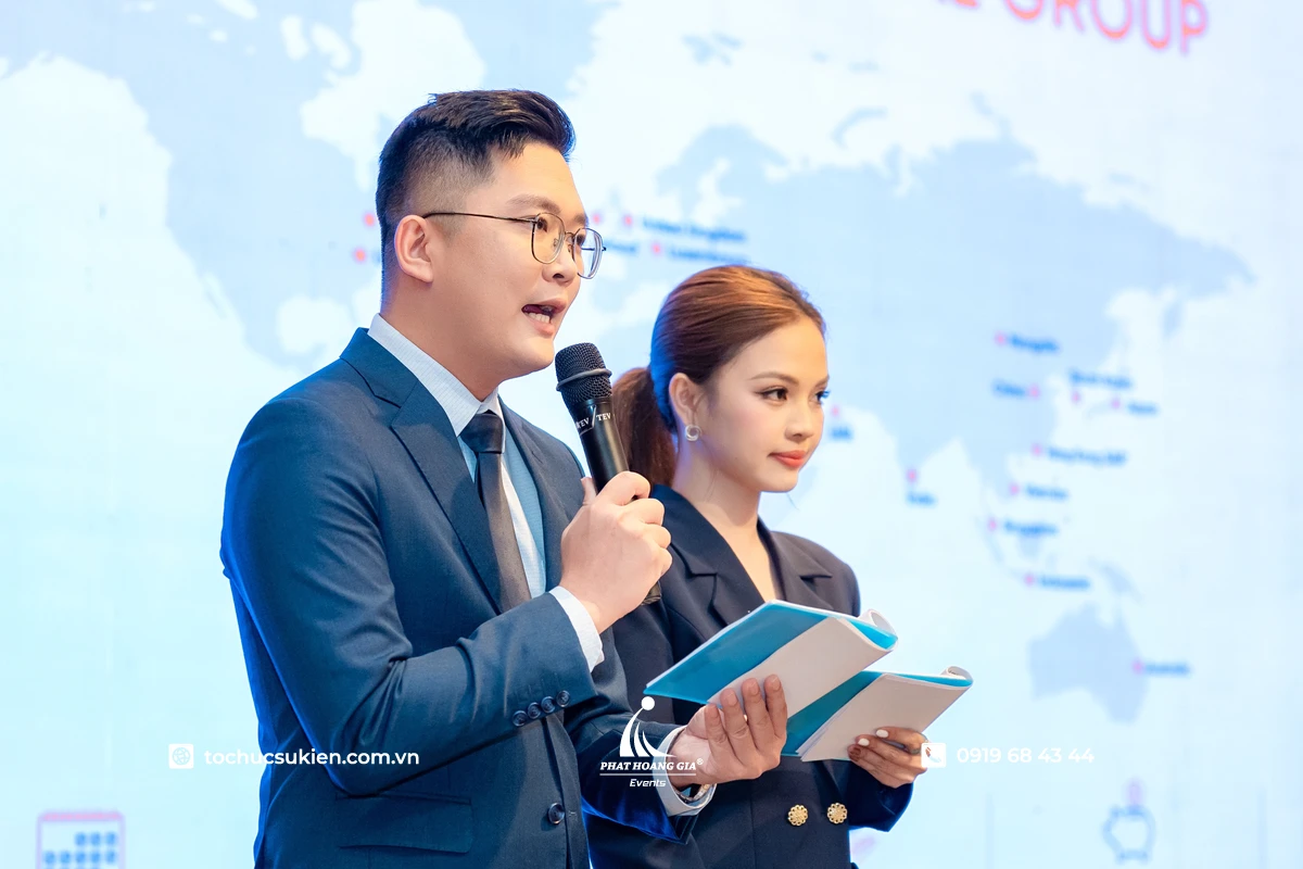 MC trên sân khấu đang dẫn chuyên nghiệp với kịch bản trên tay 