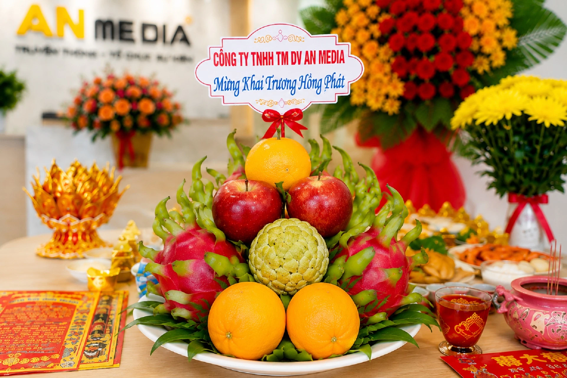 Mâm ngũ quả cúng khai trương doanh nghiệp với thanh long, táo đỏ, cam và na được bày trên bàn lễ cúng trước văn phòng công ty