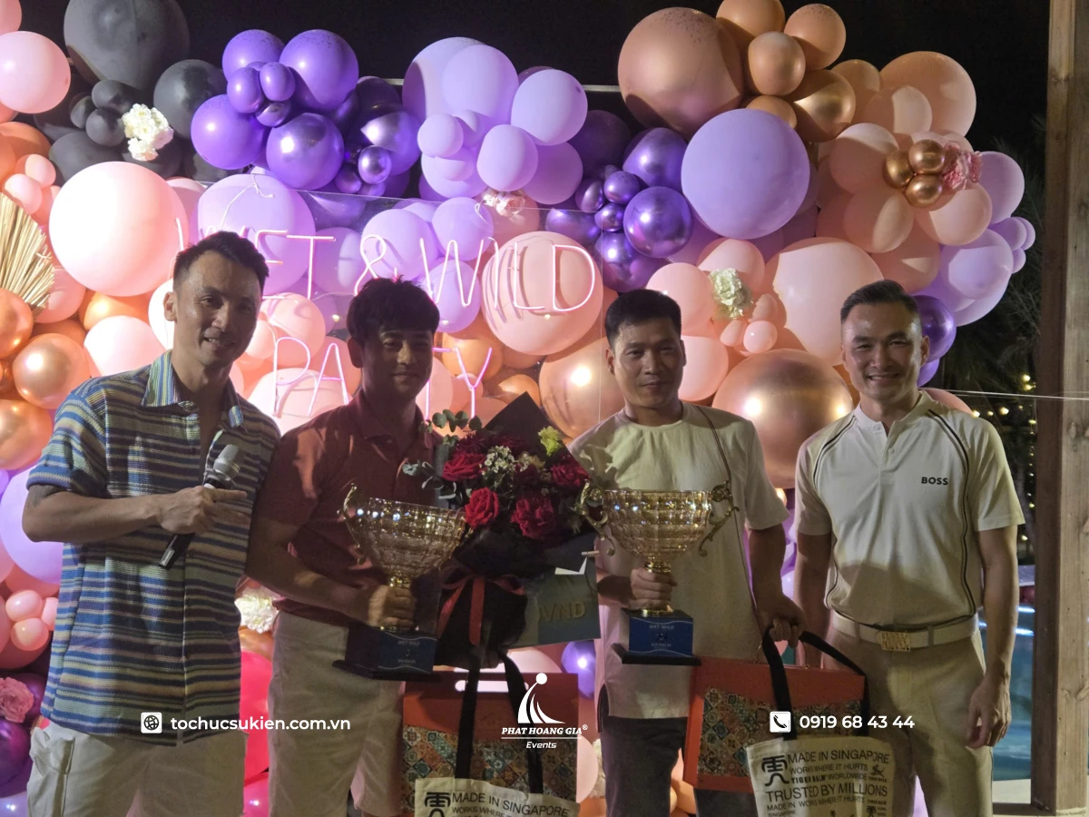 Khách mời rạng rỡ nhận cúp lưu niệm trên sân khấu sự kiện pool party ngoài trời được trang trí bong bóng