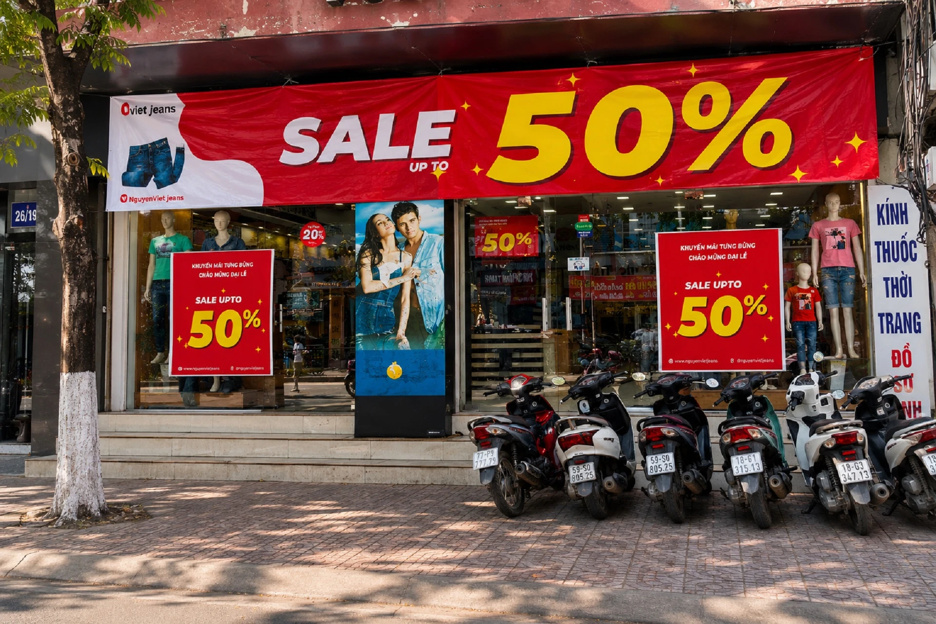 Poster khuyến mãi kết hợp banner giảm giá 50% trước cửa hàng thời trang nhằm thu hút khách hàng từ bên ngoài