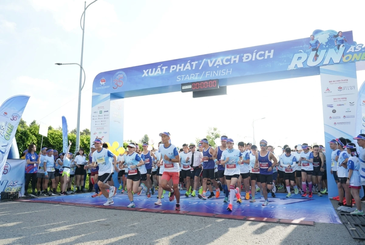 Các vận động viên mặc áo thi đấu đồng loạt xuất phát chạy qua cổng chào tại giải chạy bộ ngoài trời