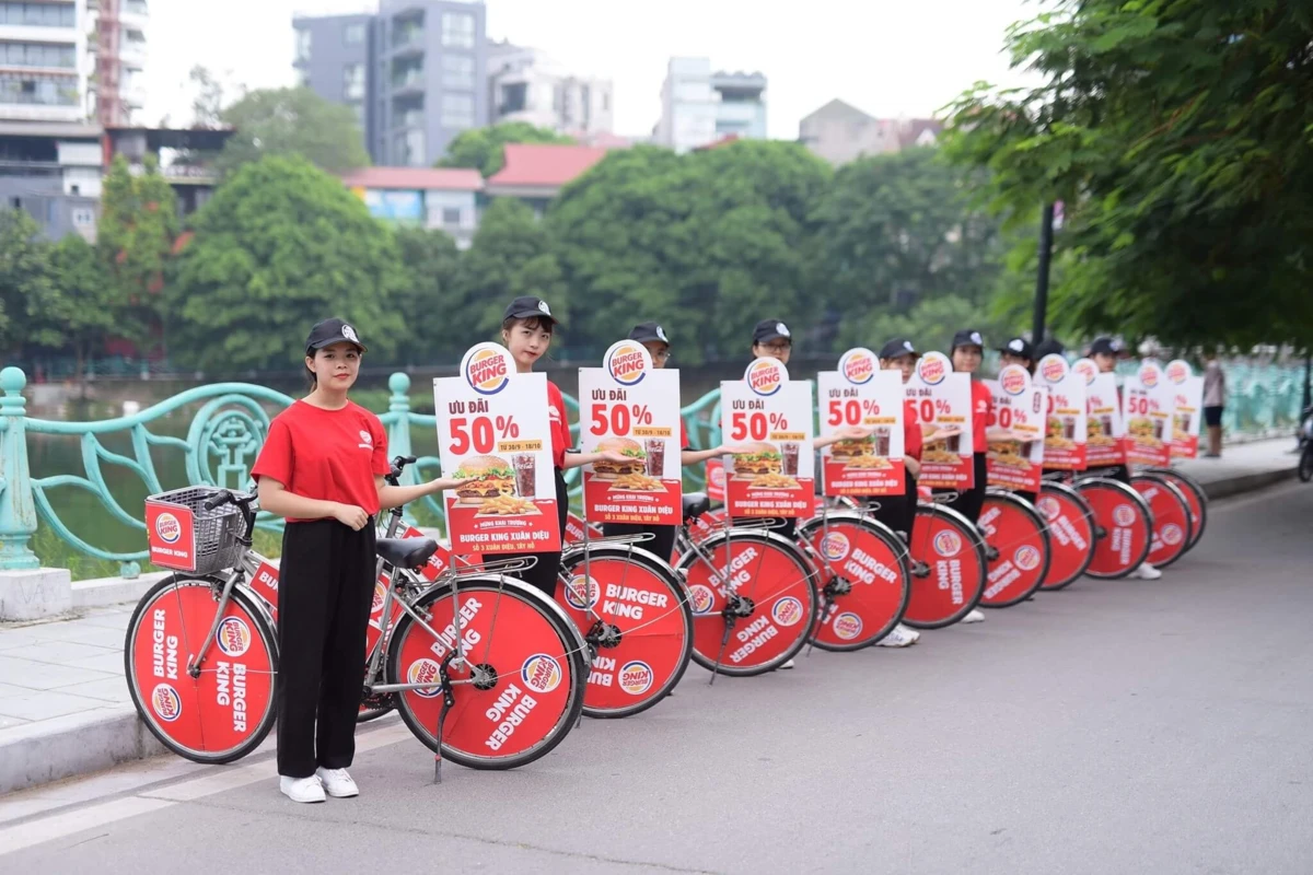 Nhân viên Burger King đứng cạnh xe đạp quảng bá chương trình giảm giá 50%.