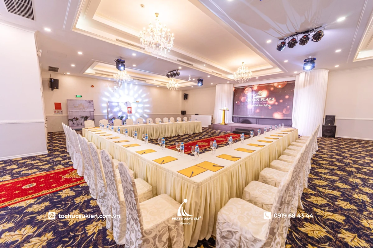 Bàn ghế chữ U phối thảm hoa văn sang trọng được setup bên trong không gian sảnh hội nghị Queen Plaza