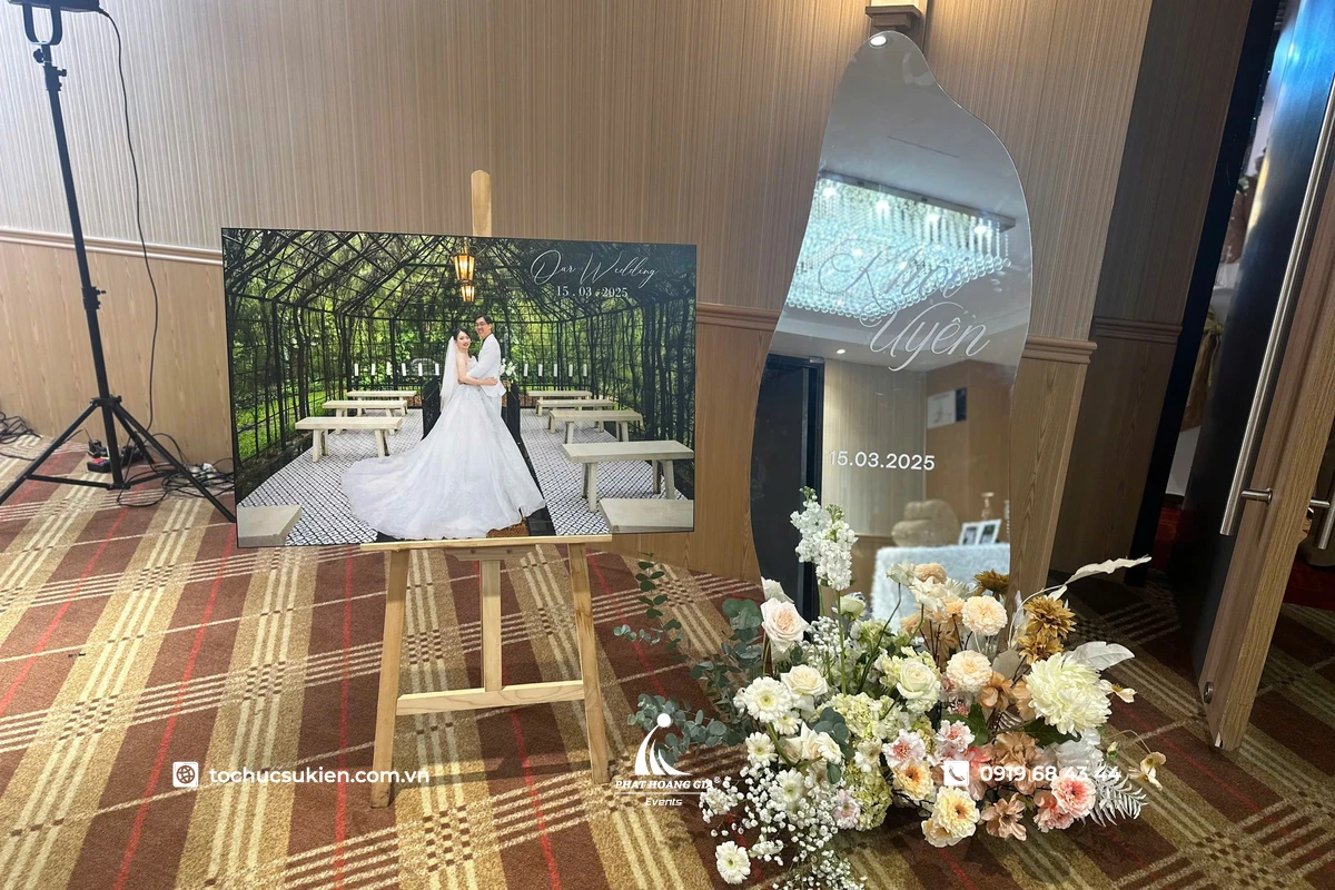 Standee chân gỗ dùng làm giá kê ảnh cưới đặt trước cổng sự kiện với thiết kế mộc mạc và tone trang trí sang trọng