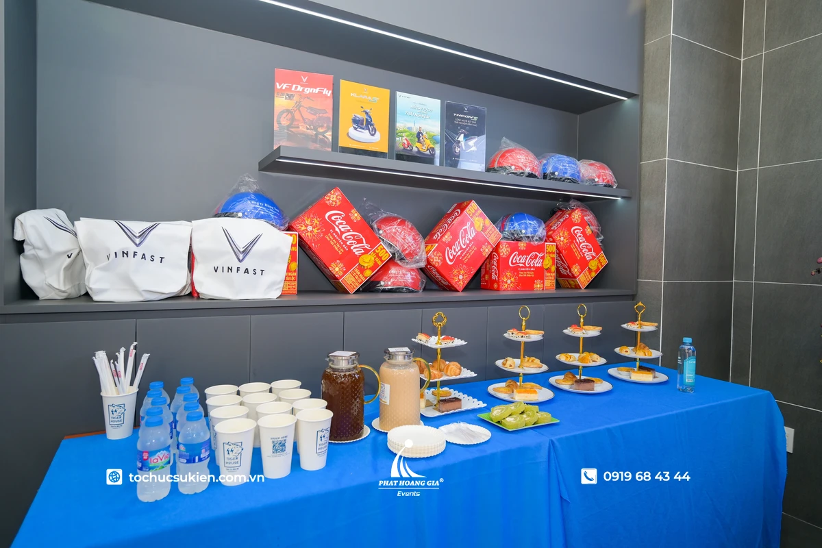 Khu vực bàn tea break được bố trí gọn gàng với các loại bánh ngọt, nước uống và các phần quà được sắp xếp phía sau trong không gian sự kiện