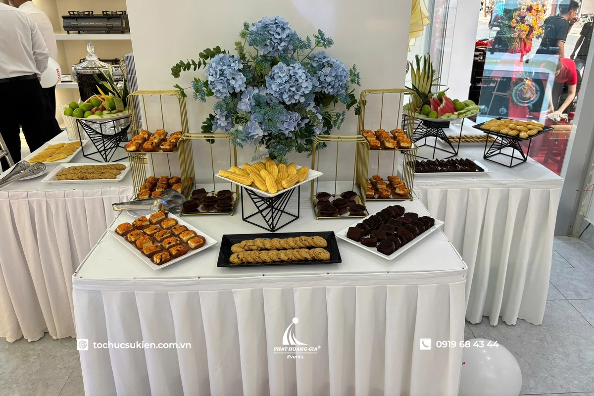Bàn menu tea break sang trọng được setup cho sự kiện quy mô lớn với các loại bánh ngọt, trái cây, nước uống và khu vực phục vụ được trang trí đồng bộ, chuyên nghiệp