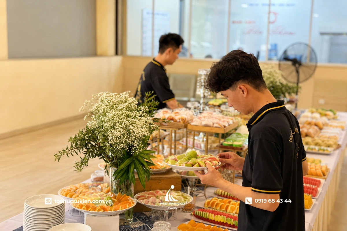 Nhân sự PHG cẩn thận kiểm tra các khay bánh ngọt và hoa quả trên bàn tiệc teabreak hội nghị