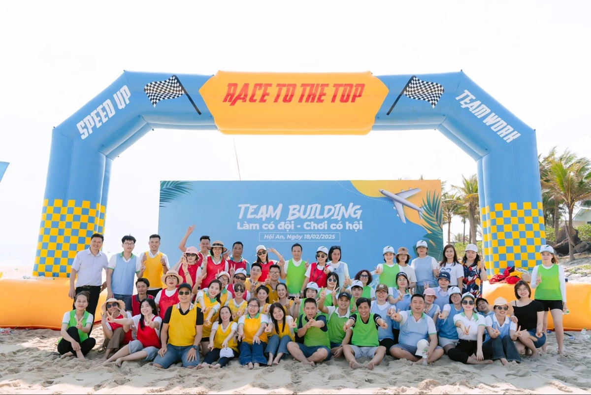 Toàn thể thành viên chụp ảnh kỷ niệm trước backdrop sân khấu teambuilding ngoài trời