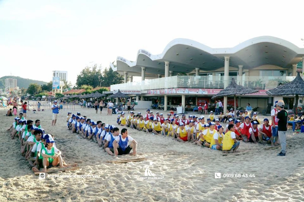Các đội chơi ngồi xếp hàng dọc tập trung trên bãi cát