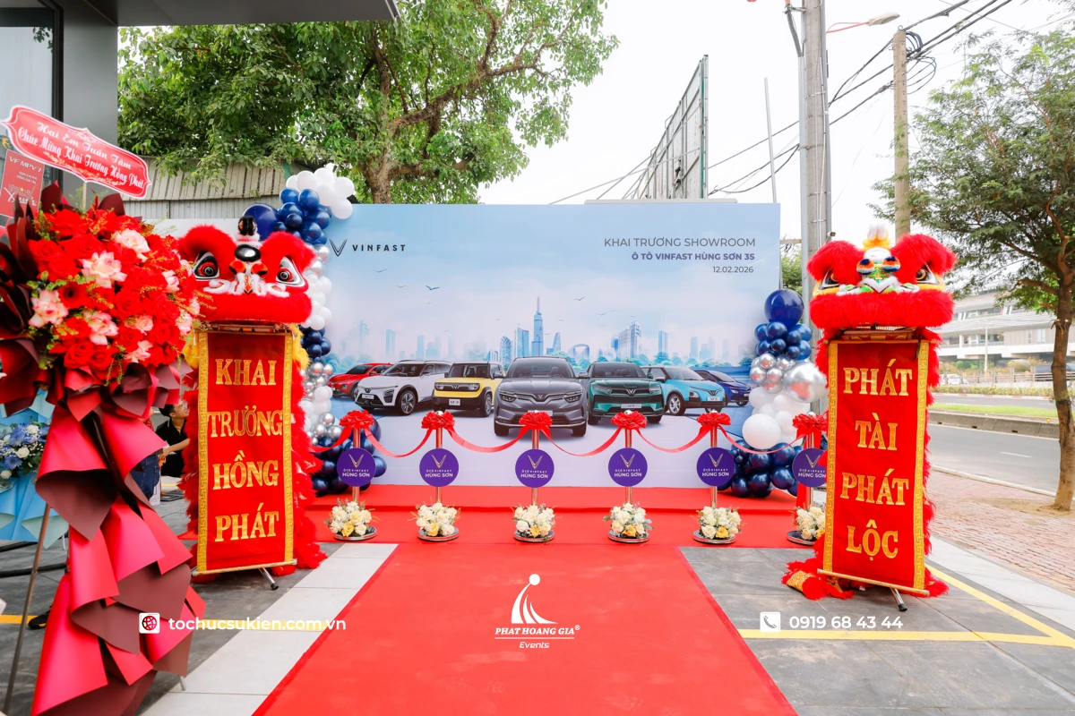Không gian lễ cắt băng khai trương showroom được trang trí thảm đỏ sự kiện và backdrop chuyên nghiệp.