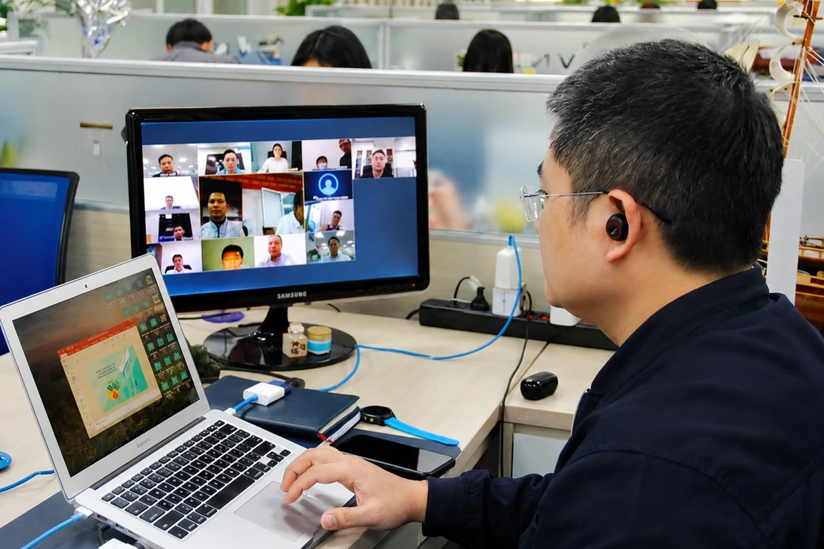 Nhân sự doanh nghiệp đang setup cuộc họp trực tuyến trên laptop và màn hình hiển thị nhiều người tham gia online