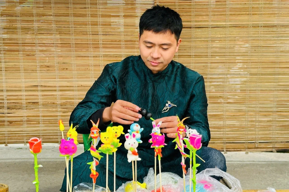 Nghệ nhân tò he đang ngồi nặn tò he thủ công tại gian hàng với nhiều kiểu dáng và phong cách tạo hình đa dạng, đầy màu sắc