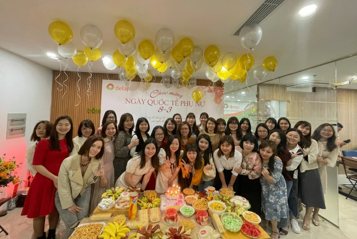 Tập thể nhân viên nữ công ty chụp ảnh kỷ niệm quanh bàn tiệc ngọt nhân dịp văn phòng tổ chức 8/3 ấm cúng