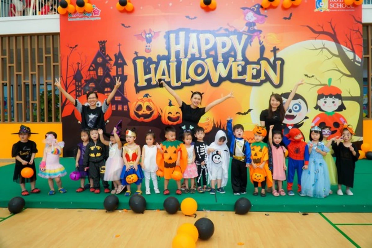 Các bé mầm non mặc đồ cosplay bí ngô và siêu nhân đứng chụp hình kỷ niệm dịp trường học tổ chức halloween