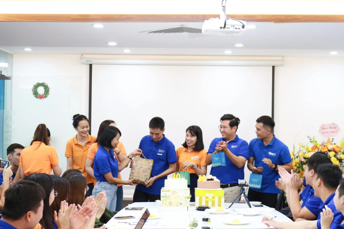 Tiệc sinh nhật tập thể nhân viên công ty tại văn phòng với bánh kem và món quà gửi tặng.