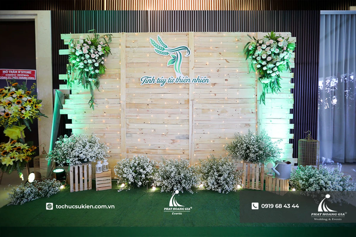 Cận cảnh khu vực check in sự kiện ra mắt sản phẩm với mẫu trang trí backdrop gỗ cùng hoa tươi