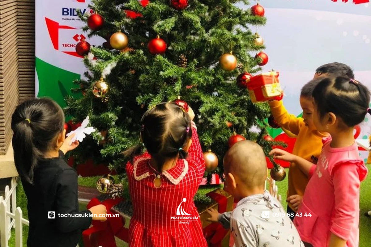 Các em nhỏ cùng nhau trang trí cây thông noel với nhiều màu sắc rực rỡ 