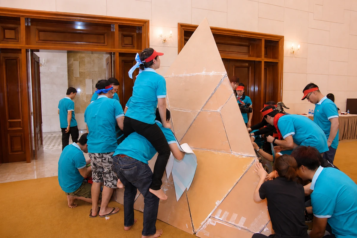 Các đội nhóm phối hợp xây tháp giấy trong trò chơi team building trong nhà đầy kịch tính.