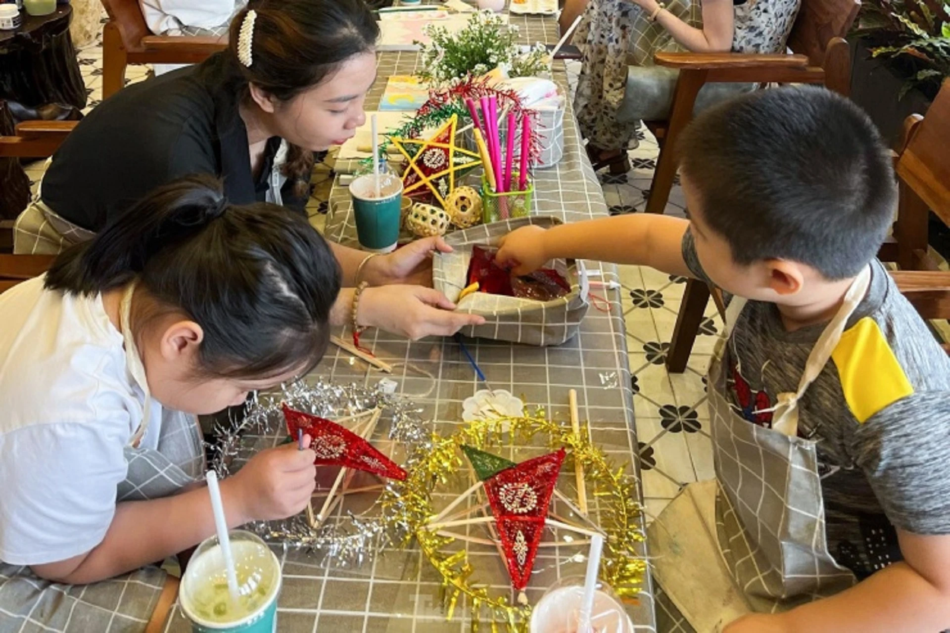 Trẻ em làm lồng đèn trung thu bằng tre dưới sự hướng dẫn của người lớn trong chương trình Trung Thu ngày nay