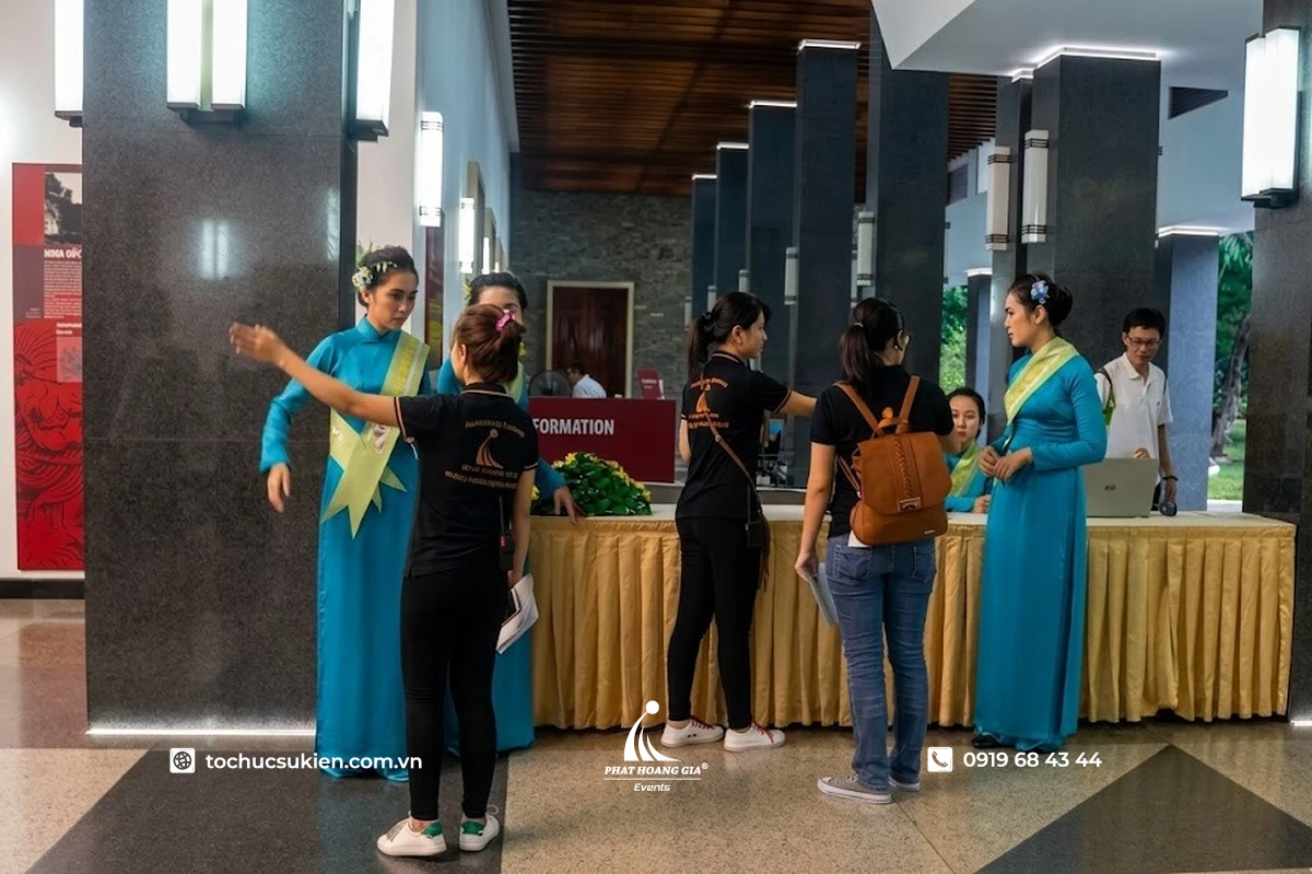 Quản lý đang hướng dẫn và điều phối nhân viên cùng PG mặc áo dài tại khu vực đón tiếp khách mời sự kiện
